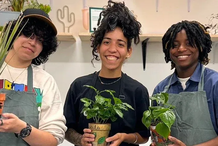 Three friends holding plants at a workshop